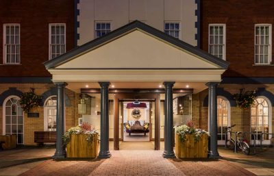 Hotel entrance decorated for Christmas with flowers and benches.