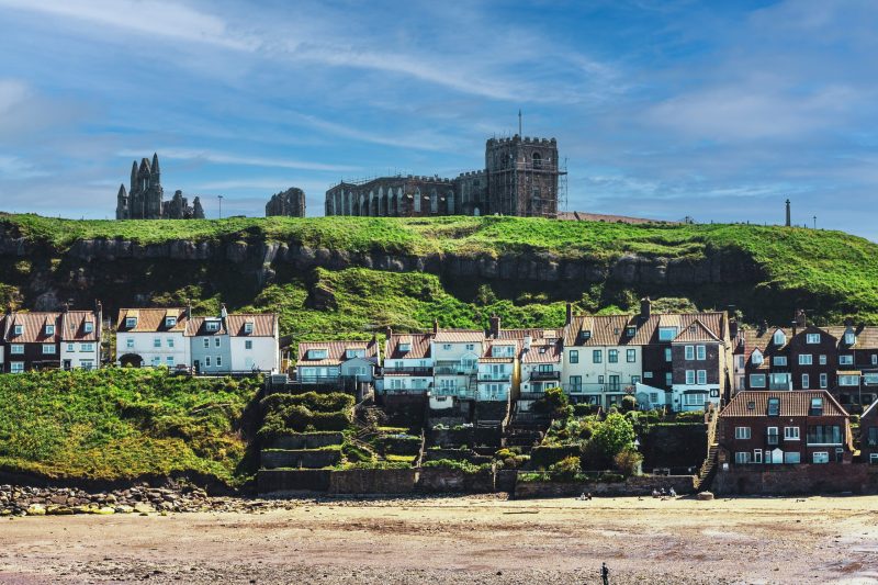 Scenic view of a historic castle overlooking a seaside town in Pennywood Tours.